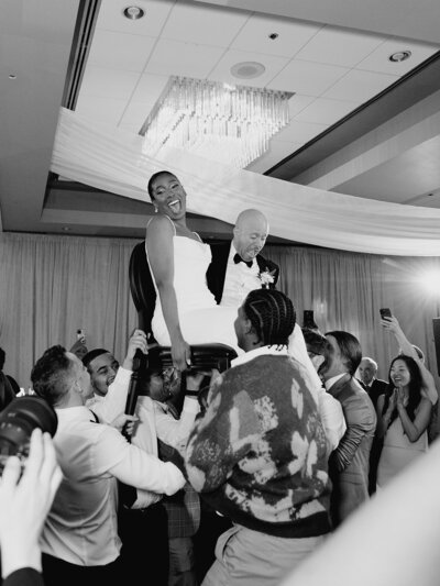 Bride and groom being carried on chairs at their wedding reception.