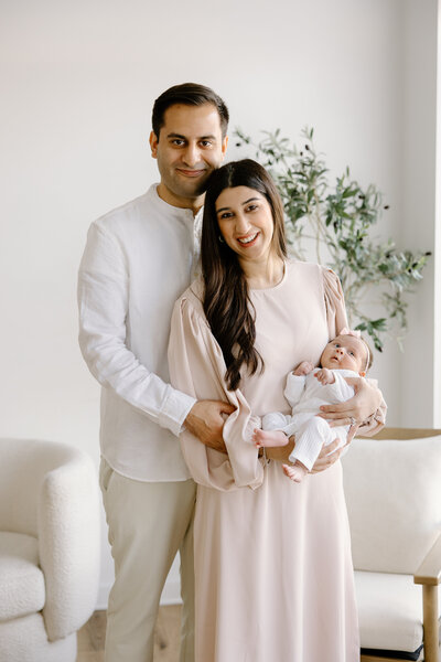 Mom and dad holding baby and smiling at camera during newborn studio session with  Indianapolis Newborn Photographer, Capturing Simplicity Photography