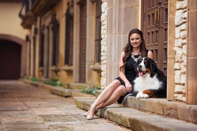 Dallas pet photographer sits on steps with her Bernese Mountain Dog.