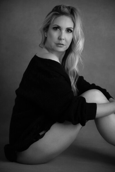blond woman wearing a black sweater posing on floor in underware