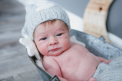 Newborn Photo taken of baby looking at the camera | Taken By Maine Photographer who photographs in places like Rangeley, Sugarloaf, Bar Harbor, and more in Maine