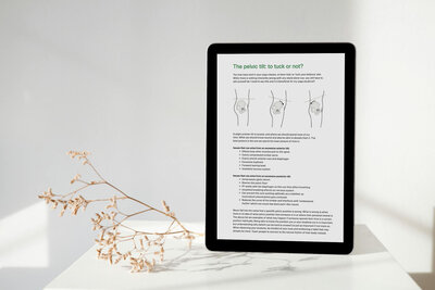 A digital tablet displayed on a white surface leaning against a textured wall with a light shadow, showing a page from an anatomy course titled 'The pelvic tilt: to tuck or not?' with descriptive text and illustrative diagrams, accompanied by dried plants in the foreground, suggesting a study environment.