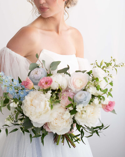 a closeup photo of a bride in a strapless dress holding a white, pink and blue bouquet.  Captured by Ottawa wedding photographer JEMMAN Photography