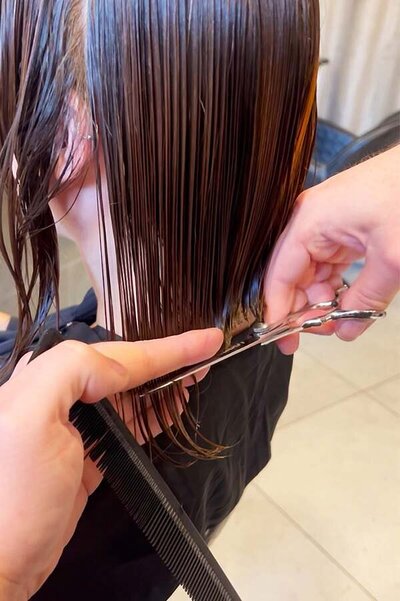 Precision haircut on wet brunette hair using scissors and comb, showcasing professional salon techniques at Blake & Kwan Cronulla.