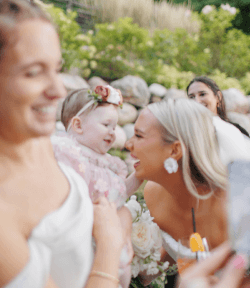 A bride smiling as she's looking at a baby
