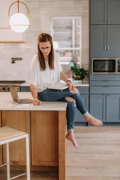 Liz Strong sitting on kitchen island writing on sticky notes