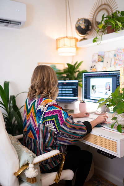 Designer sitting at desk designing a website on Showit - Create & Wander