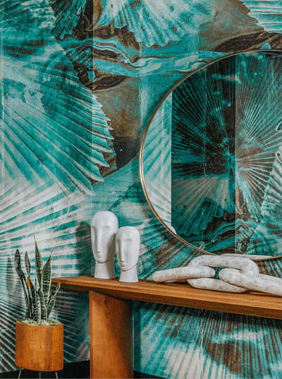 Artful entryway at The LC in West Hollywood featuring abstract teal wallpaper, a wooden console, and decorative sculptures.