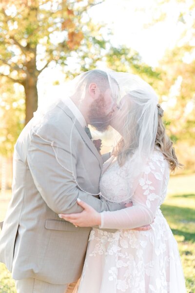 Bride and groom sharing an intimate moment with their noses touching, smiling under the bride's veil