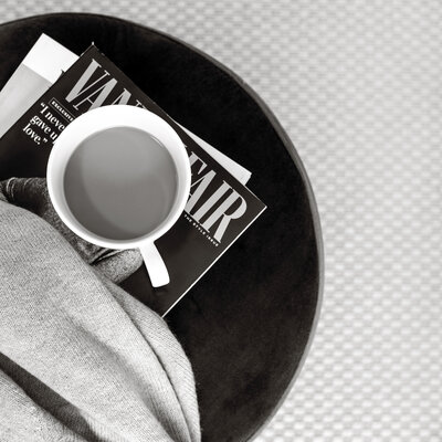 Coffee cup on a soft gray blanket with a Vanity Fair magazine, reflecting calm, intentional branding for modern entrepreneurs