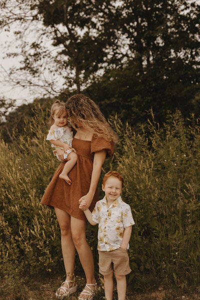 Woman holding toddler and holding hand of child on bluff in La Crosse, Wisconsin