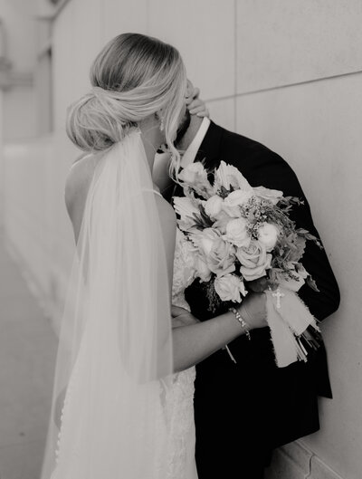 timeless black and white image of bride cuddling groom in downtown wichita kansas on their wedding day