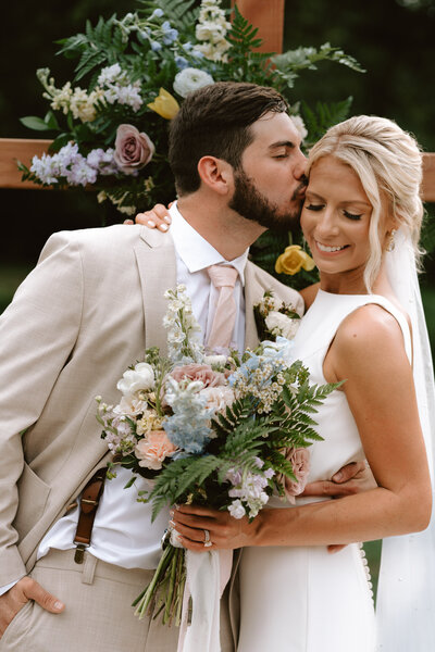 Groom kisisng brides cheek