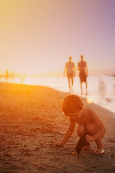 boy playing on beach at sunset