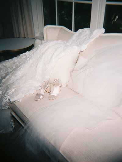 Flash film photo of wedding dress and shoes laying on a couch