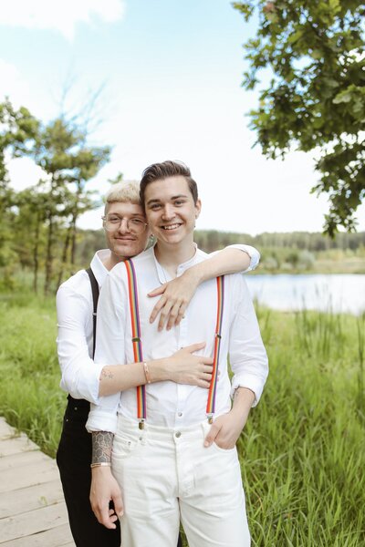 A groom hugging his husband from behind.