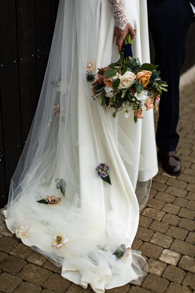 Bride long veil trailing on floor with flower bouquet