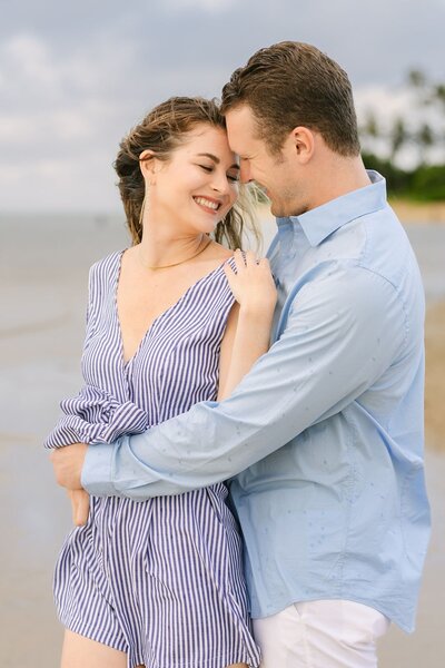A man and woman embrace each other on the beach of Kauai.