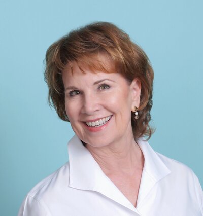 woman with short brown hair wearing a white shirt and smiling