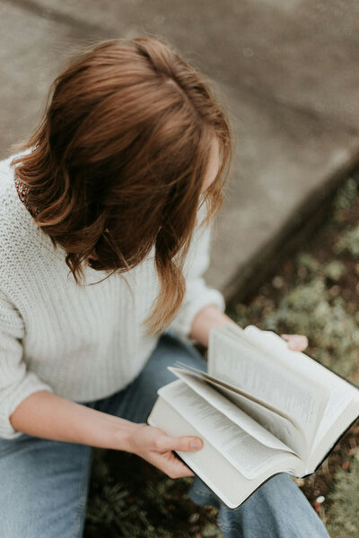 woman reading bible on a curb