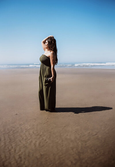 Family Photographer, a woman stands at the beach with her hands in her hair