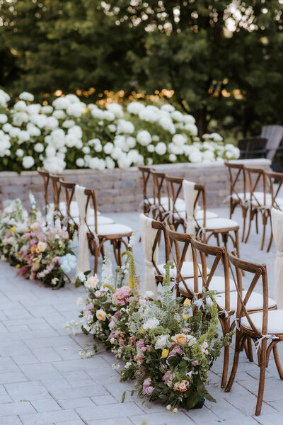 wedding ceremony flowers and crossback chairs on the stone patio at Willowbrook wedding venue