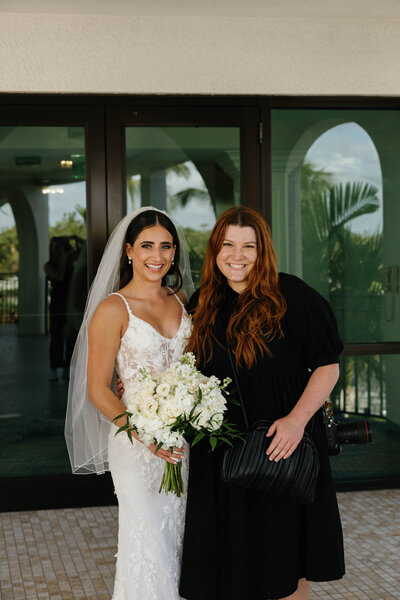 Cassandra standing with her bride and groom smiling at the camera