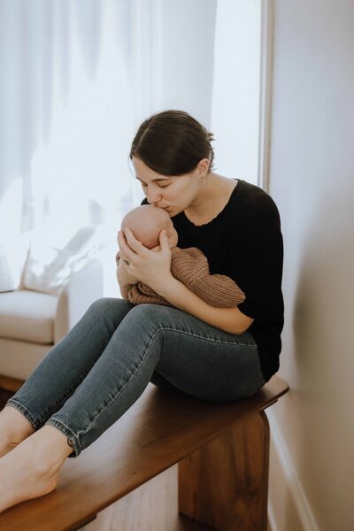 A family of four sits on their front porch, smiling at the camera during a Warner Robins at home family session. The parents sit behind their young son and daughter, while autumn decorations hang on the front door.