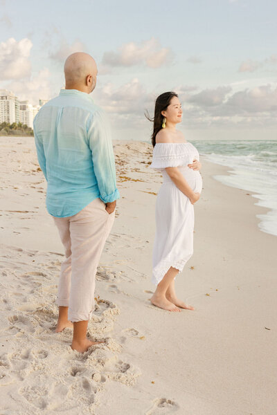 Expecting couple standing on the sand during a maternity session at Miami Beach in South Florida.