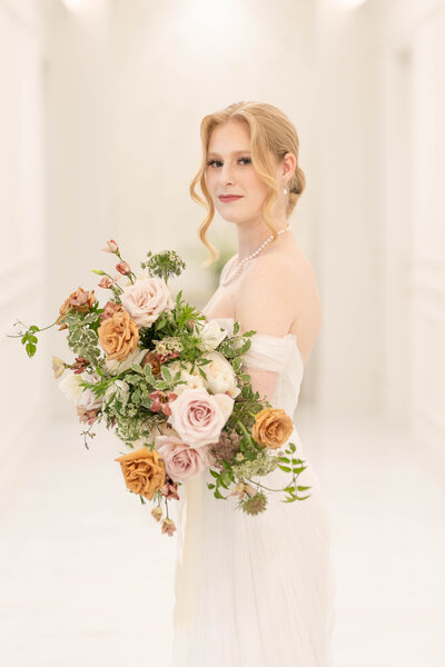 A neutral color  Bridal bouquet with Blush pink roses, toffee roses, butterfly, red, ranunculus, Queen Anne’s lace, and Jasmine