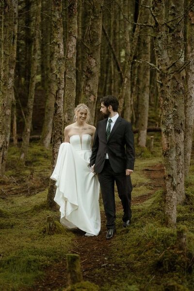 Couple stand on a rock and hold hands after their wedding in Loch Lomond, Scotland