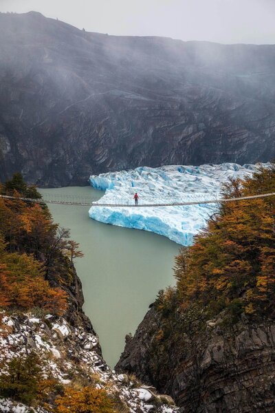 Person walking on the suspension bridge in Patagonia looking at Grey Glacier while hiking the W-trek in Torres del Paine national park Chile