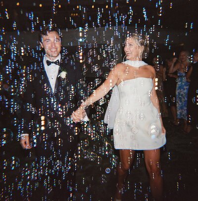 Bride and groom walking in front of vintage car.