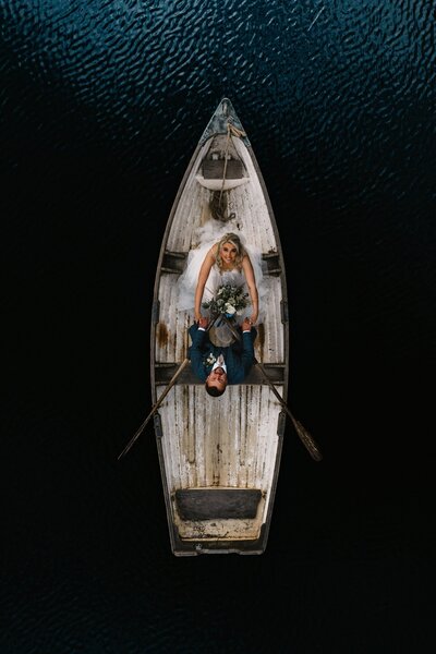 bride and groom looking up while in row boat