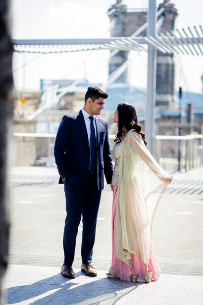 Experience the vibrant and colorful celebration of Divya and Dhruv’s Indian engagement shoot set against the iconic backdrop of Cincinnati’s Roebling Bridge. This stunning photograph captures the couple in traditional Indian attire, their rich fabrics and intricate designs complementing the historic architecture of the bridge. Perfect for couples looking for engagement photo inspiration that beautifully blends cultural heritage with distinctive urban landscapes, this image is a testament to love and tradition amidst the beauty of Cincinnati.