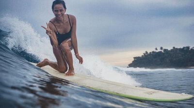 local longboard legend showing peace fingers while riding her surfboard