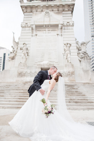 bride and groom doing a dip kiss at Monument Circle photographed by Kaitlin Mendoza Photography, a wedding photographer in Indianapolis