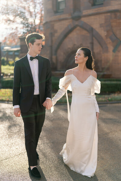Bride and groom walk hand-in-hand with golden sunlight glow