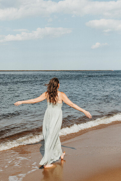 Elizabeth walking on beach with arms open wide