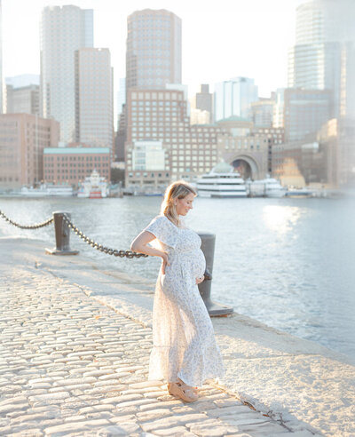 pregnant woman wearing floral dress poses for photos at the boston seaport