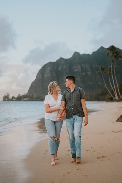 a beautiful couple walking on the beach in oahu hawaii