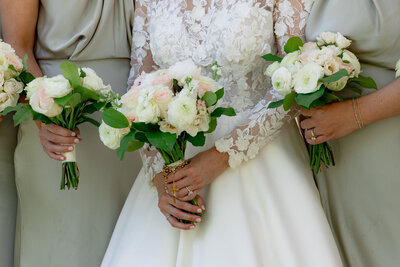 woman in white holding a bouquet in the center of woman in taupe dresses holding bouquets