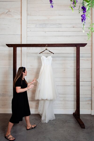 Photo assistant hanging wedding dress for photos