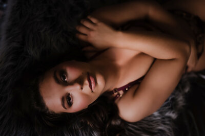 A close up of a woman laying on a bed in red lingerie