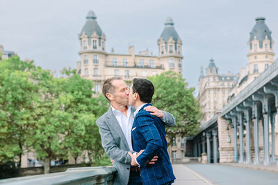 Gay couple kissing near the Eiffel Tower at Bir-Hakeim Bridge during a romantic Paris photoshoot — captured by photographer Rachael Laporte
