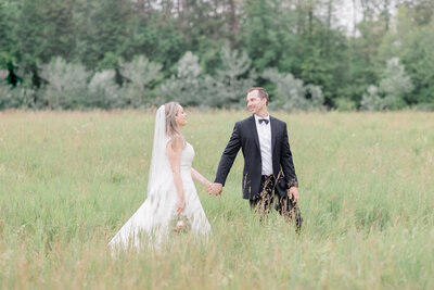 Bride and groom walking through long grassy field at Mill of Kintail photographed by Ottawa wedding photographer, Brittany Navin Photography