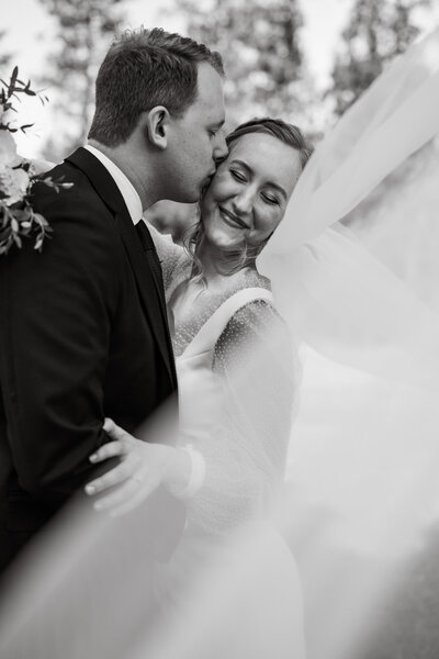 Bride and groom kissing under veil taken by Boise wedding photographer.
