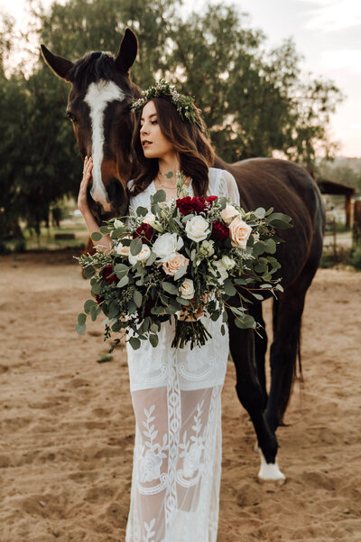 Boho bride petting horse taken by Orange County wedding photographer Mikey Mora Photography