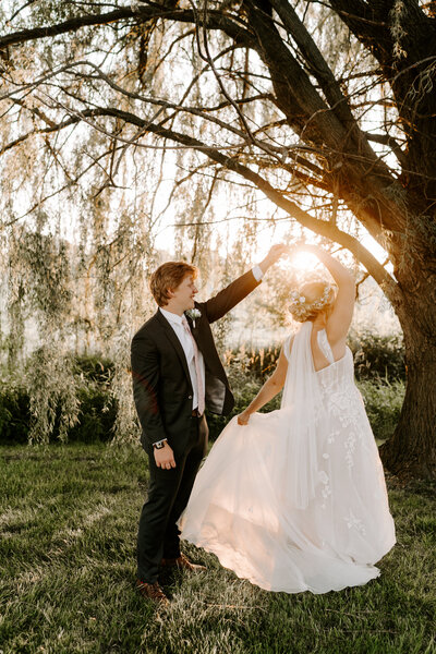 Couple twirls after exchanging vows in the golden sunset.