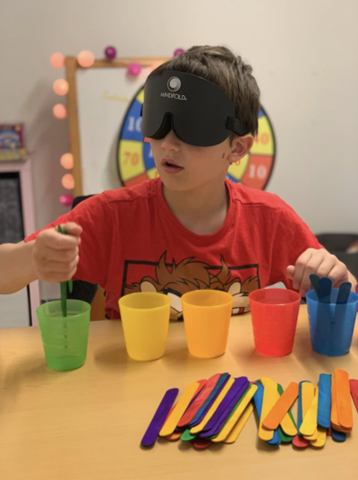 chlapeček s maskou na očích třídí barevné tyčinky podle barev